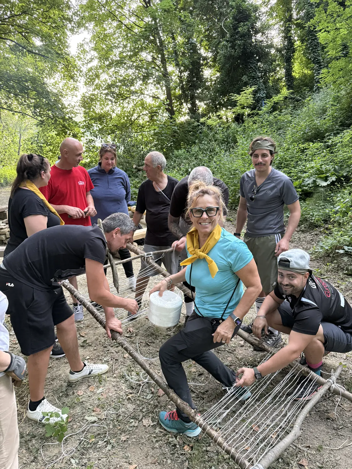 Team aziendale che costruisce una barella di soccorso con legno e corda durante un team building BOSCO PRO